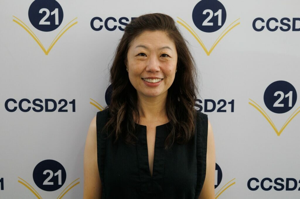 woman standing in front of a step-and-repeat with district logos emblazoned on it