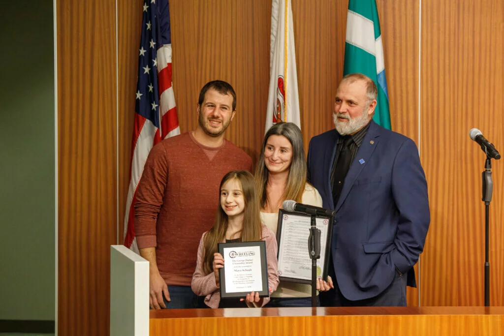 Maya stands with her parents and Village President Patrick Horcher shortly after receiving her award