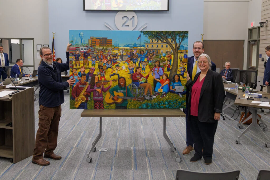 Steve Hamann (left), art teacher at Holmes Middle School, stands next to his newly unveiled painting for the CCSD21 district office with Dr. Michael Connolly, superintendent, and Board President Debbi McAtee