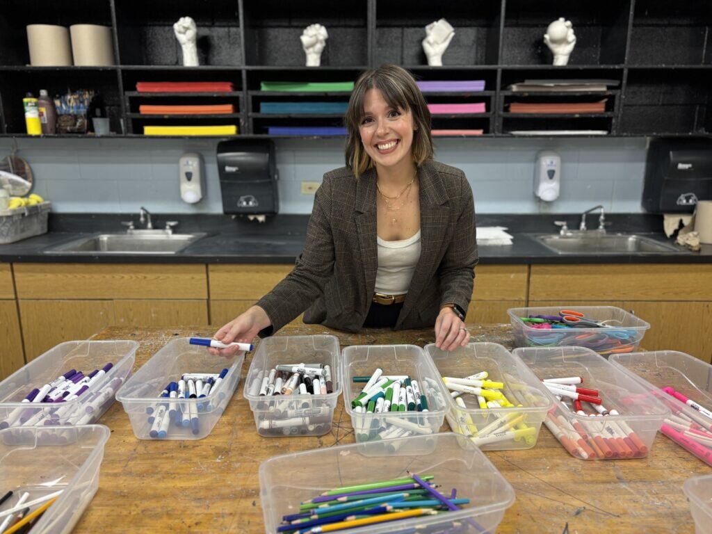 Picture of art teacher Lauren Hirsh sitting at a table with art supplies.